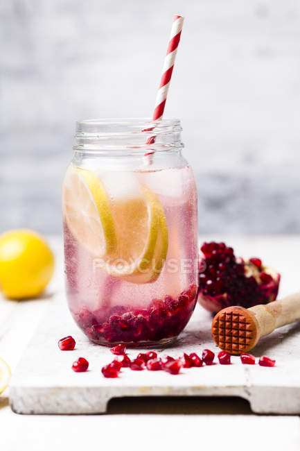Fruit infused water with lemon slices, crushed pomegranate seeds and sparkling water — Stock Photo