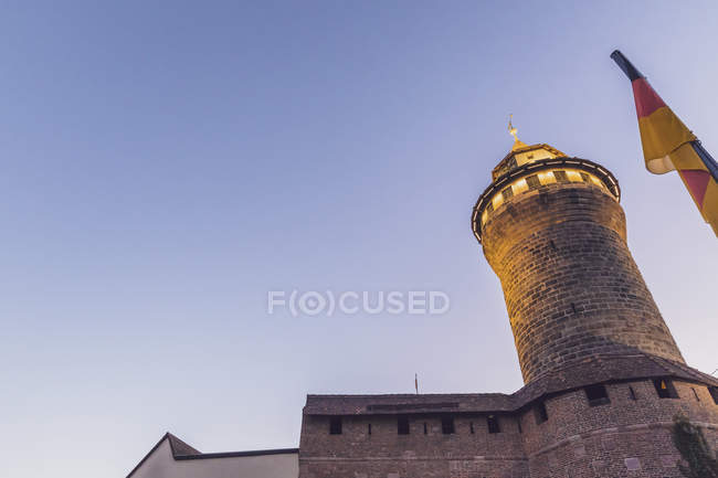 Germania, Norimberga, Castello di Norimberga, Torre Sinwell e bandiera tedesca all'ora blu, vista angolo basso — Foto stock