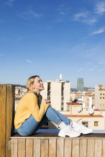 Young woman relaxing on an urban rooftop terrace — Stock Photo