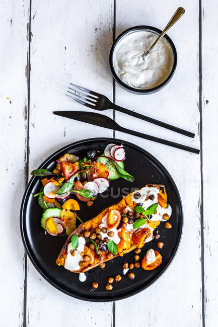 Сладкий картофель с овощами и соус тахини со смешанным салатом — стоковое фото