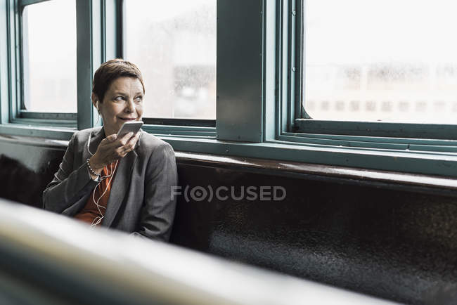 Businesswoman on a ferry with cell phone and earphones — Stock Photo