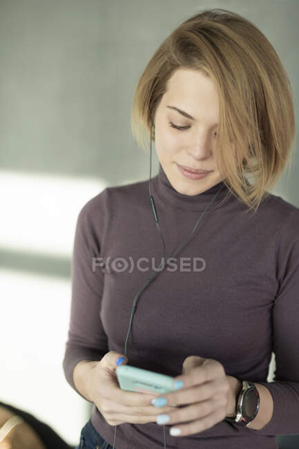 Junge Frau im Büro, Smartphone mit Kopfhörer — Stockfoto