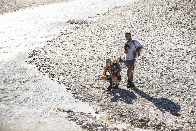 Áustria, Alpes, casal em uma viagem de caminhada fazendo uma pausa em um riacho — Fotografia de Stock