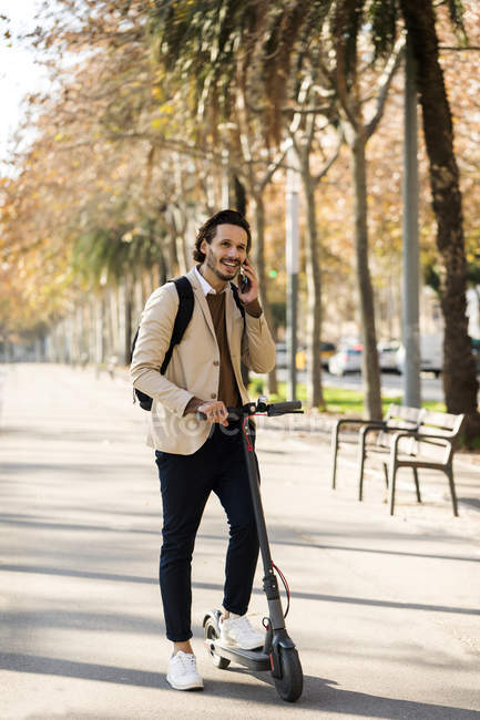 Man with backpack and E-scooter on the phone — Stock Photo