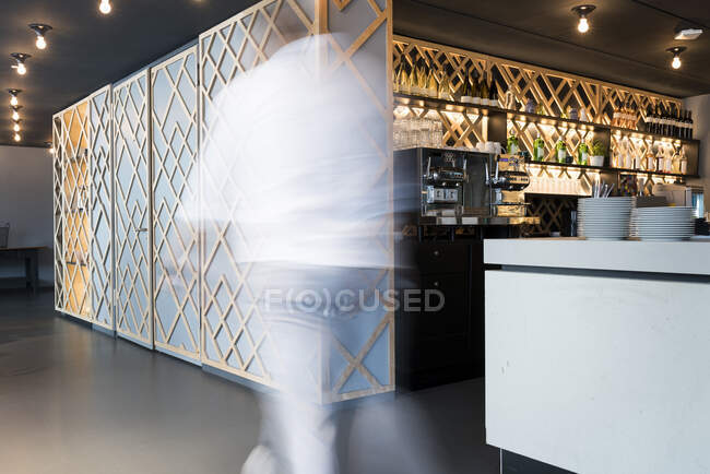Blurred man walking past modern office lounge area and bar — Stock Photo