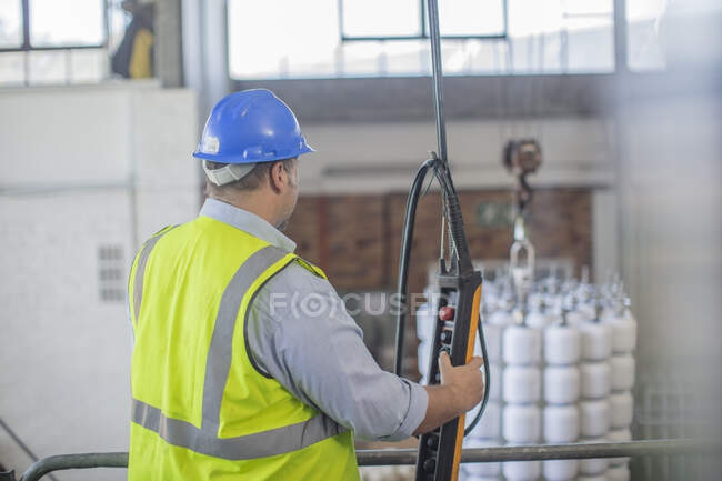 Hombre usando el control de funcionamiento del sombrero duro en fábrica - foto de stock