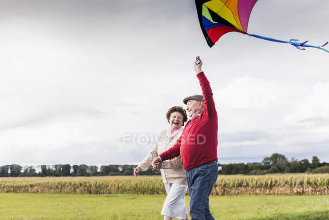 Heureux couple aîné avec cerf-volant dans le paysage rural — Photo de stock