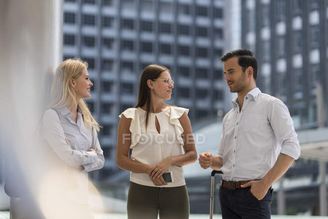 Smiling business colleagues talking in the city in front of skyscraper — Stock Photo