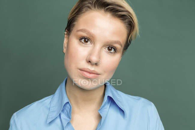 Портрет молодой женщины с пирсингом носа на зеленом фоне — стоковое фото