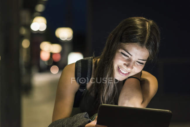 Retrato de mujer joven con auriculares y tableta esperando en la estación por la noche — Stock Photo