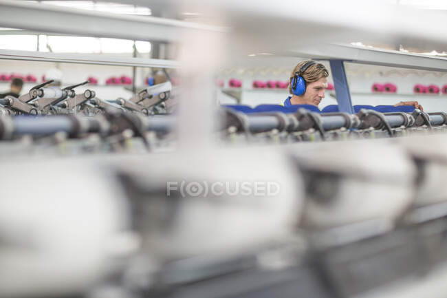 Mann mit Ohrenschützer bedient Maschine in Fabrik — Stockfoto