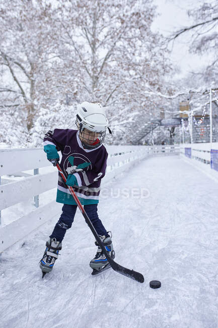 Мальчик играет в хоккей на катке — стоковое фото