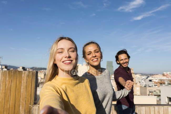 Des amis s'amusent sur un toit-terrasse urbain, se tenant la main — Photo de stock