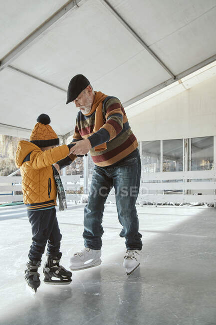 Дедушка и внук на катке, катание на коньках — стоковое фото