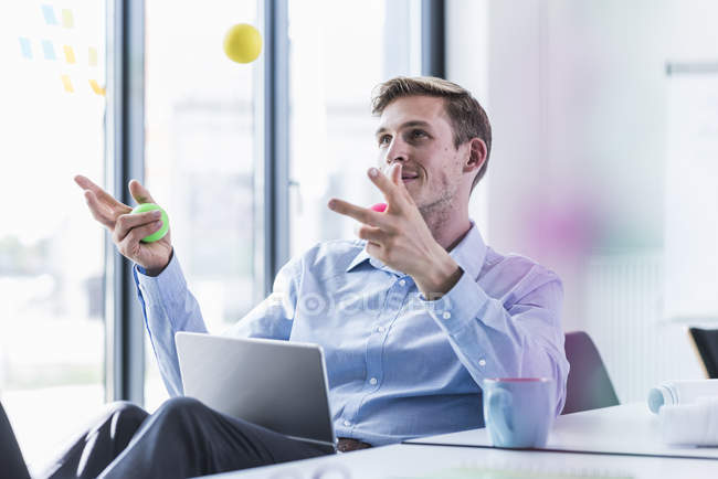 Businessman juggling with balls in office — Stock Photo