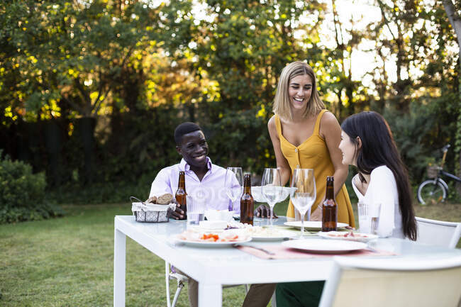 Host serving food at a summer dinner in the garden — Stock Photo