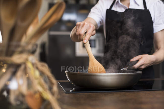 Nahaufnahme einer Frau, die in der Küche mit einer Pfanne kocht — Stockfoto