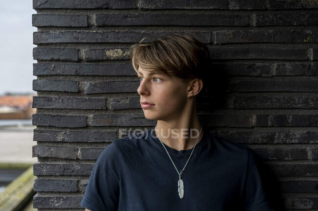 Portrait of young man leaning against a wall — Stock Photo