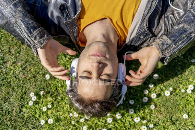 Uomo sdraiato sul prato fiorito con cuffie — Foto stock