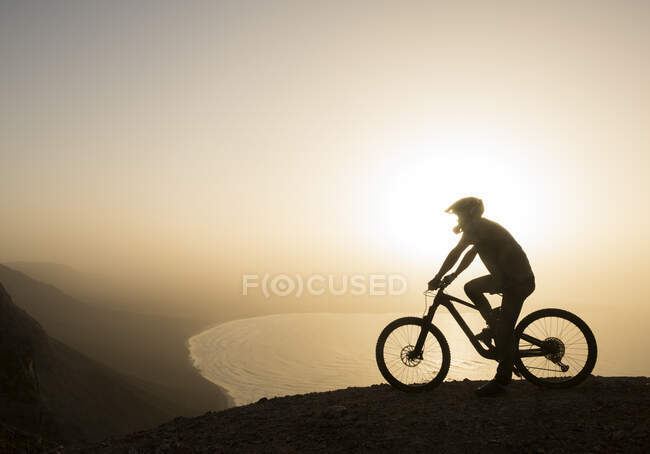Spagna, Lanzarote, mountainbiker in gita sulla costa al tramonto godendo della vista — Foto stock