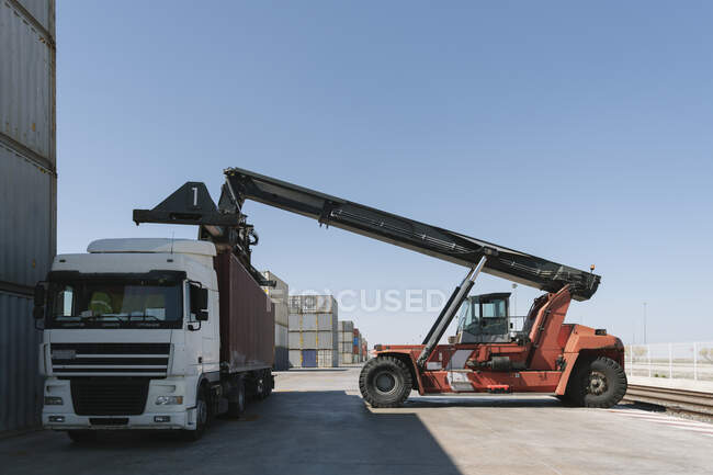 Guindaste que levanta contêiner de carga no caminhão no local industrial — Fotografia de Stock