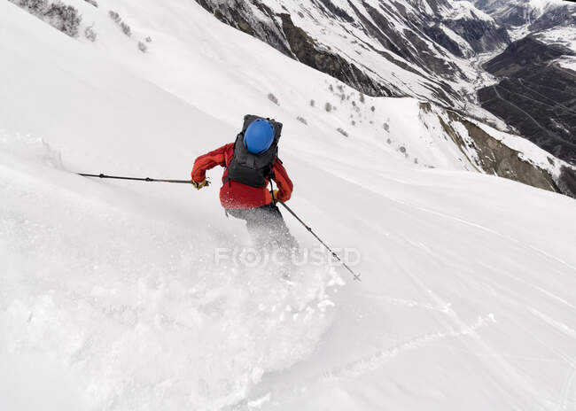 Georgia, Cáucaso, Gudauri, hombre en una excursión de esquí cuesta abajo - foto de stock