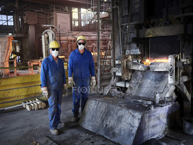 Industry, Smeltery: Workers in front of blast furnace with helmet and dust mask — Stock Photo