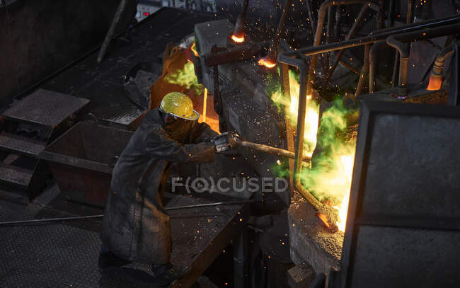 Industria, trabajador en el horno durante la fusión de cobre, con un traje de proximidad al fuego - foto de stock