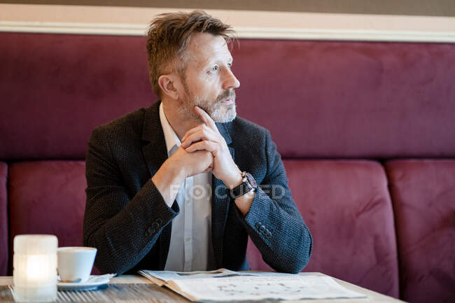 Pensive mature businessman with newspaper in a coffee shop — Stock Photo