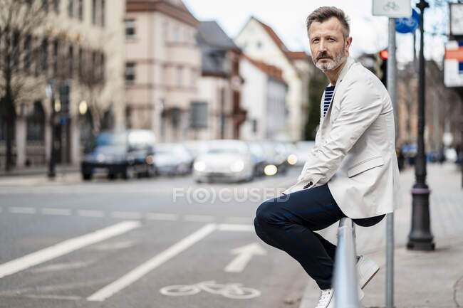 Deutschland, Zwickau, Porträt eines reifen Mannes, der an einem Geländer in der Stadt sitzt — Stockfoto