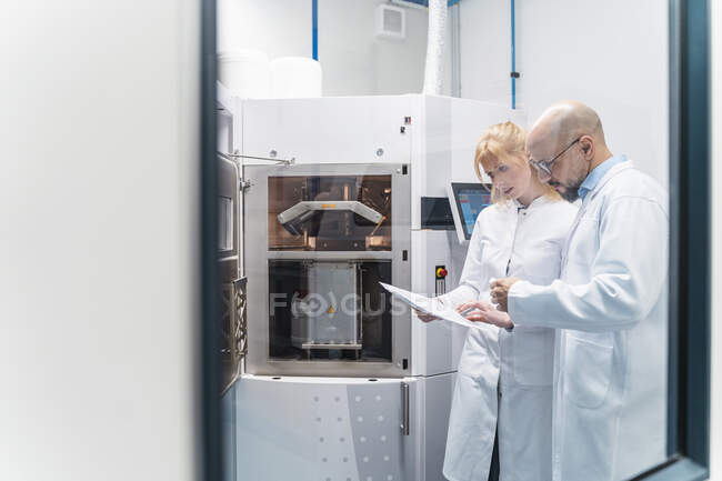 Two technicians wearing lab coats looking at plan — Stock Photo