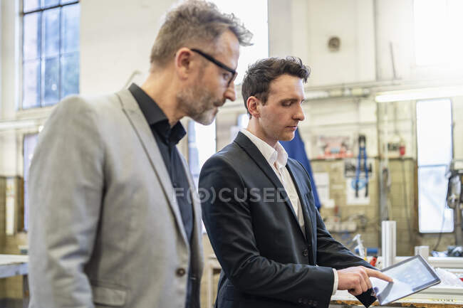 Dos hombres de negocios con tablet en una fábrica - foto de stock