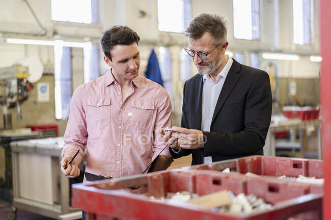 Due uomini in fabbrica esaminano il pezzo — Foto stock