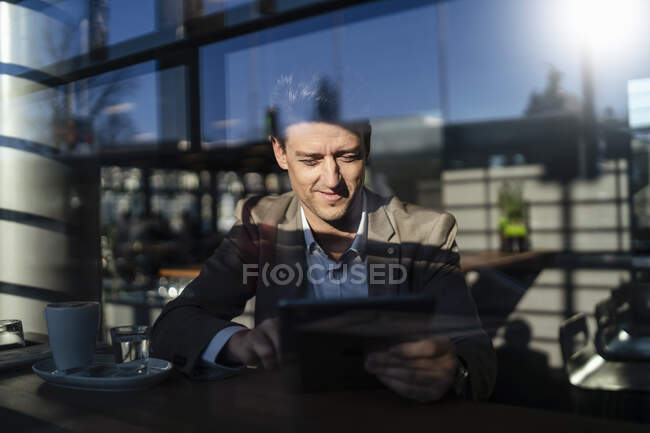 Geschäftsmann mit Tablet hinter dem Fenster in einem Café — Stockfoto