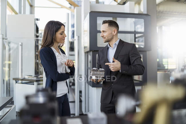 Empresario y empresaria discutiendo pieza de trabajo en fábrica - foto de stock