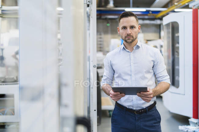 Portrait of businessman using tablet in a modern factory — Stock Photo