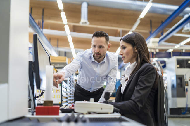 Geschäftsmann und Geschäftsfrau unterhalten sich am Computer in moderner Fabrik — Stockfoto