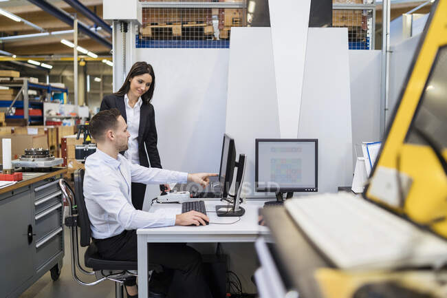 Homme d'affaires et femme d'affaires parlant à l'ordinateur dans l'usine moderne — Photo de stock