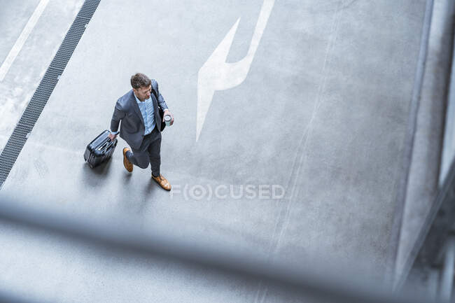 Vista dall'alto dell'uomo d'affari che cammina con bagaglio e caffè da  asporto — grigio, una persona - Stock Photo