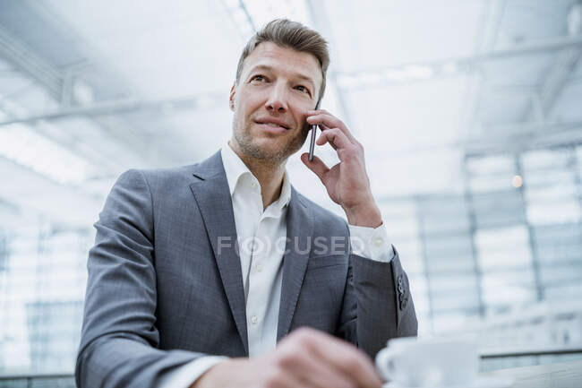 Businessman on cell phone in a cafe — Stock Photo