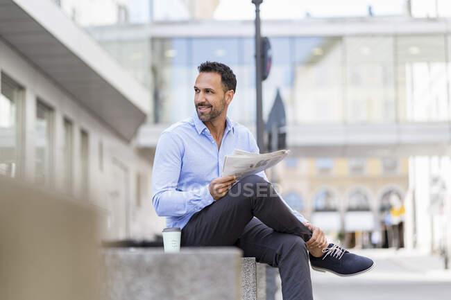 Businessman reading newspaper in the city — Stock Photo
