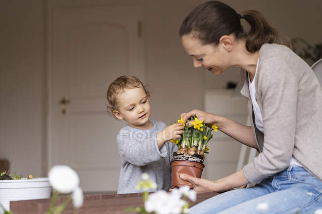 Madre e hija plantando flores juntas en el balcón - foto de stock
