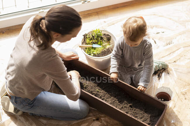 Mother and daughter with flower box on balcony — Stock Photo