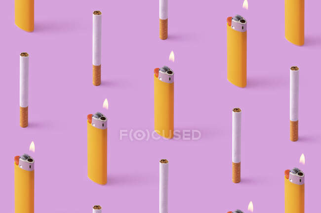 Linhas de cigarros e isqueiros em chamas no fundo roxo — Fotografia de Stock