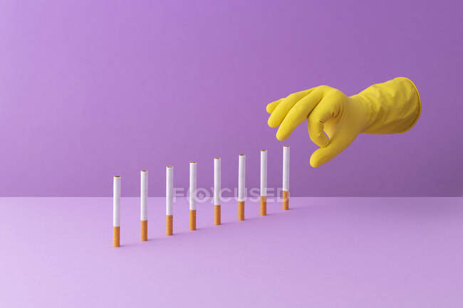 Mão empurrando cigarros em uma fileira, criando um efeito dominó — Fotografia de Stock