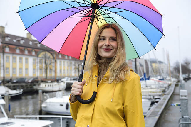 Denmark, Copenhagen, smiling woman with colourful umbrella at city harbour — Stock Photo