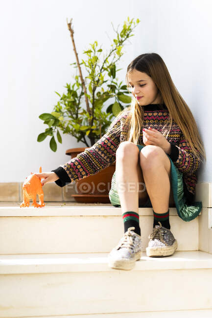 Girl playing with dinosaur toy at home - foto de stock