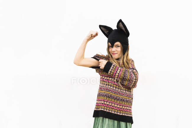 Porträt eines Mädchens, das vor weißer Wand im Fledermauskostüm die Muskeln spielen lässt — Stockfoto