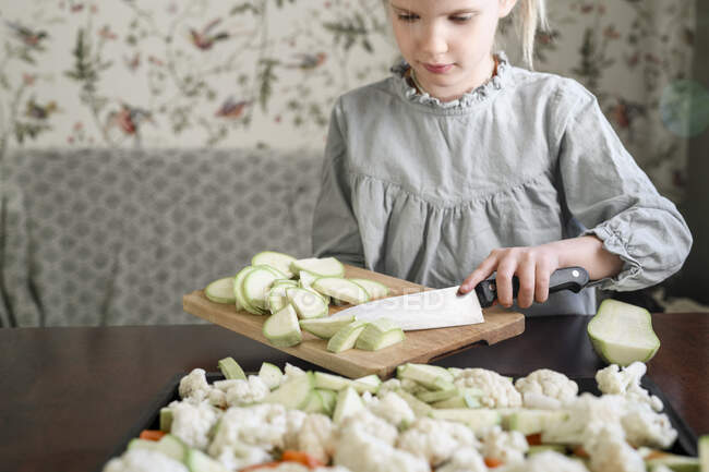 Girl slicing vegetables indoors — Stock Photo