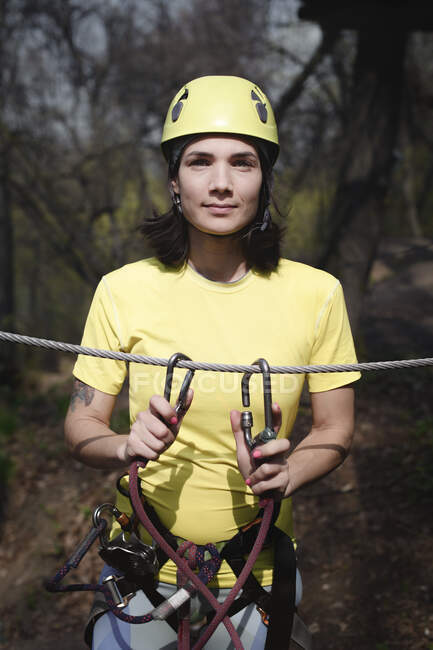 Молодая женщина в жёлтой футболке и шлеме на веревке — стоковое фото